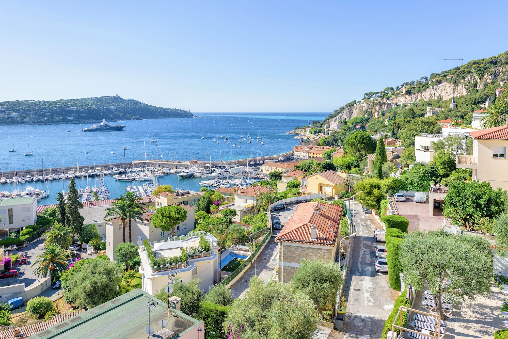 Daylight view to city buildings, port and yachts cruising on water. Blue sky and ocean